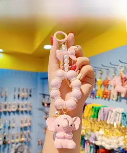 Detail of pink resin elephant keychain featuring a crown, pearls, and a pink ribbon bow