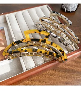 Detailed macro view of acetate hair claws in amber and marble patterns on a beige tray