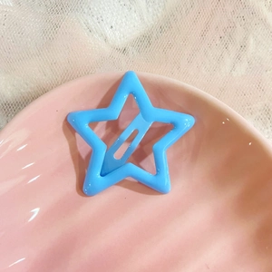 Close-up of a sky blue star-shaped hair clip on a pink shell tray with white lace