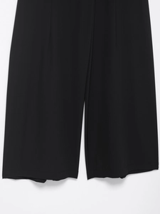 Detail view of smooth black wide-leg trousers fabric and straight leg opening hem