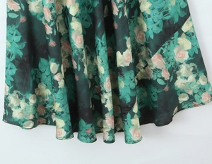 Gros plan d'une robe vert foncé avec motifs de roses et détails de tissu drapé