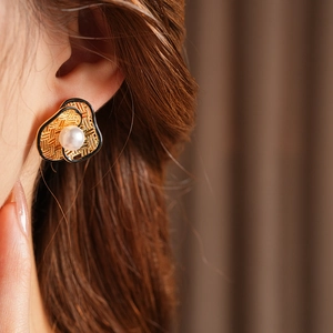 Close-up of vintage flower pearl earrings with black enamel trim on female model ear