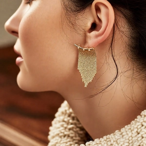 Détail de boucles d'oreilles à pompons en maille plaquée or 14K avec zircons sur modèle