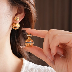 Gros plan de boucles d'oreilles vintage en or 18k avec sphères creuses et gemmes colorées