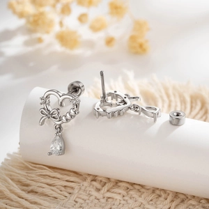 Silver bow and heart stud earring with teardrop pendant on a white display stand