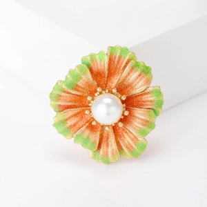 Exquisite orange and green enamel flower brooch with large white pearl on white pedestal