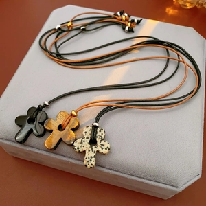 Detailed view of three adjustable wax cord necklaces with cross-shaped stone pendants