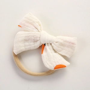 Détail du bandeau en mousseline pour bébé avec pois orange sur tissu de coton doux