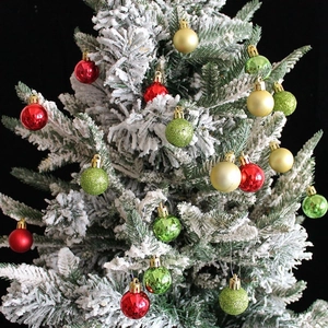 Rote goldene und grüne Weihnachtskugeln mit Glitzer und Mattenoberfläche auf verschneitem Baum