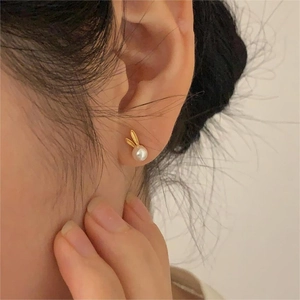 Close-up of model wearing cute gold rabbit pearl stud earrings in 925 sterling silver