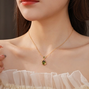 Close-up of gold plated necklace with green zircon pendant on a model's collarbone