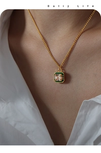 Detail shot of a square zircon pendant with green enamel on a gold titanium steel necklace