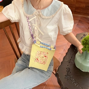 Broderie détaillée d'étoiles et de cerises sur un mini sac bandoulière en toile jaune vif