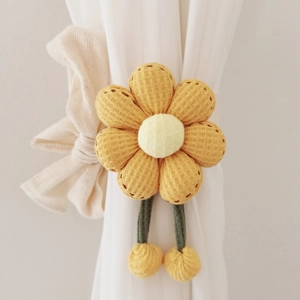 Yellow knitted sunflower curtain tieback with plush balls on a white curtain