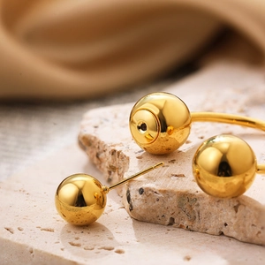 Macro shot of polished gold spherical stud earrings on stone base with high gloss finish