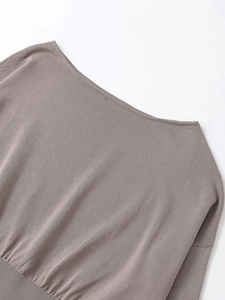 Gros plan sur un pull en maille taupe montrant la texture fine et le col bateau évasé