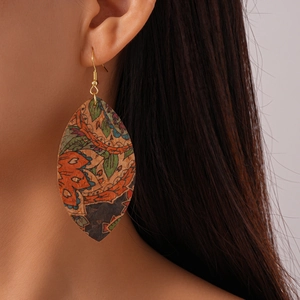 Close-up of bohemian leaf-shaped leather earrings with vintage geometric print on model