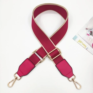 Close-up of fuchsia and beige woven shoulder strap with gold metal hooks and buckle