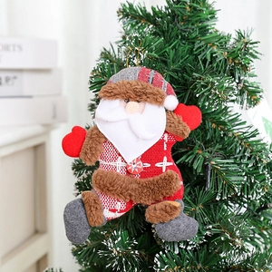 Dettaglio di un Babbo Natale di peluche appeso ai rami verdi di un albero di Natale
