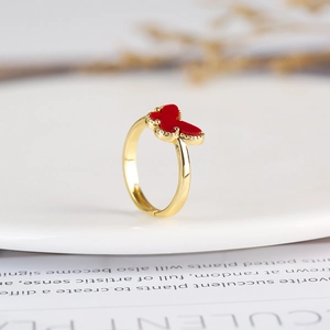 Detailed close-up of a red butterfly ring in gold finish on a rustic vintage background