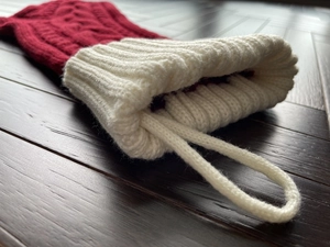 Detailed close-up of knit Christmas stocking with cable pattern and hanging loop on wood