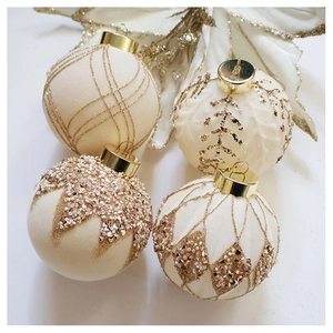 Close-up of four creamy white flocked Christmas baubles with gold glitter and beads