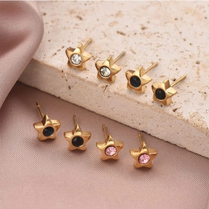Vue macro de boucles d'oreilles étoile dorées avec cristaux roses, noirs et clairs