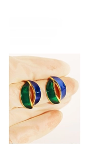 Detail of vintage geometric enamel earrings featuring green and blue interlaced wavy lines