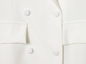 Vue détaillée du blazer blanc à double boutonnage avec des poches à rabat élégantes