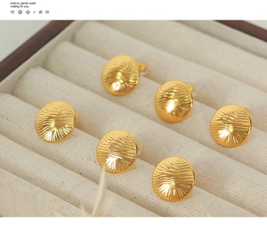 Macro detail of three pairs of elegant gold titanium steel earrings with water wave textures