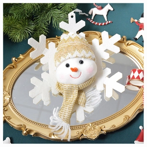 Close-up of a plush snowman head with gold knit hat on a white snowflake base