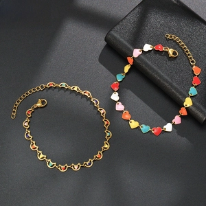 Detail view of gold-plated chain bracelet with colorful enamel heart and moon charms