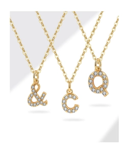 Close-up of three gold necklaces with crystal-encrusted C, Q, and ampersand letter pendants