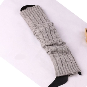 Detailed macro view of the thick cable knit pattern on light grey winter leg warmers
