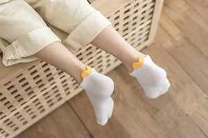 Detail of white cotton mesh socks with yellow wavy heel tabs and breathable texture