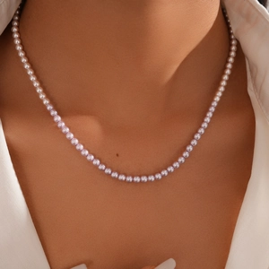Detail of gradient pearl necklace showing off-white to pink transition on model neck
