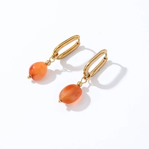 Detailed macro view of golden rectangular hoops with orange translucent stone pendants