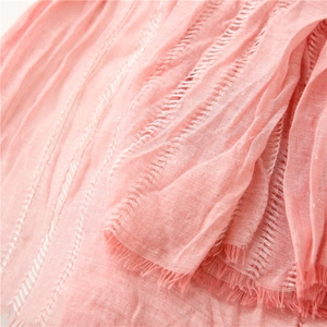 Close-up of soft pink linen-textured scarf featuring hollow-out weave and delicate fringe edges