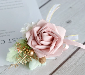 Close-up of a handmade dusty pink rose boutonniere with golden berries and lace ribbons