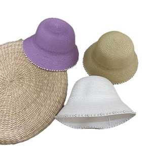 Detail of straw sun hats with elegant pearl trim in purple, beige, and white colors