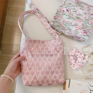 Detailed close-up of pink floral and heart-patterned satin tote bags on a white table