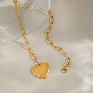 Detailed view of a gold heart pendant necklace on chunky link chain with ribbed glass decor
