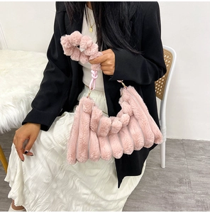 Close-up of pink plush handbag with pleated texture and knotted strap on a model