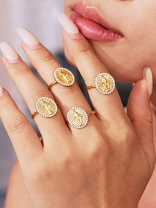 Detailed view of four gold 18K oval rings with Virgin Mary carving and zircon inlay