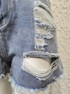 Détail d'un short en jean bleu clair avec déchirures et ourlet effiloché à franges