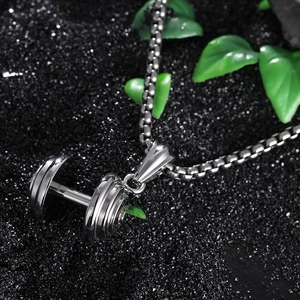 Macro d'un pendentif haltère en acier inoxydable avec finition polie sur une chaîne box