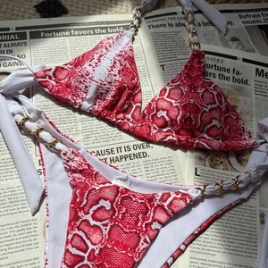 Gros plan d'un bikini à motif serpent rouge et blanc avec chaînes dorées décoratives