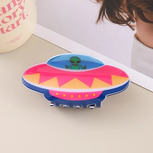 Macro shot of unique UFO hair claw clip with alien design in pink and blue acetate