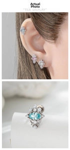 Macro detail of oval zircon and pearl piercing studs shown on ear in silver finish