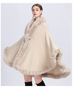 Detail view of beige knit poncho featuring thick faux fur collar and wavy hemline texture